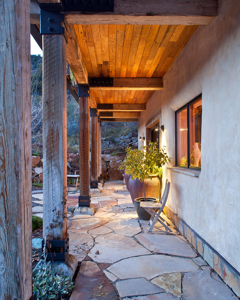 Aménagement d'une terrasse montagne avec des pavés en pierre naturelle et une extension de toiture.