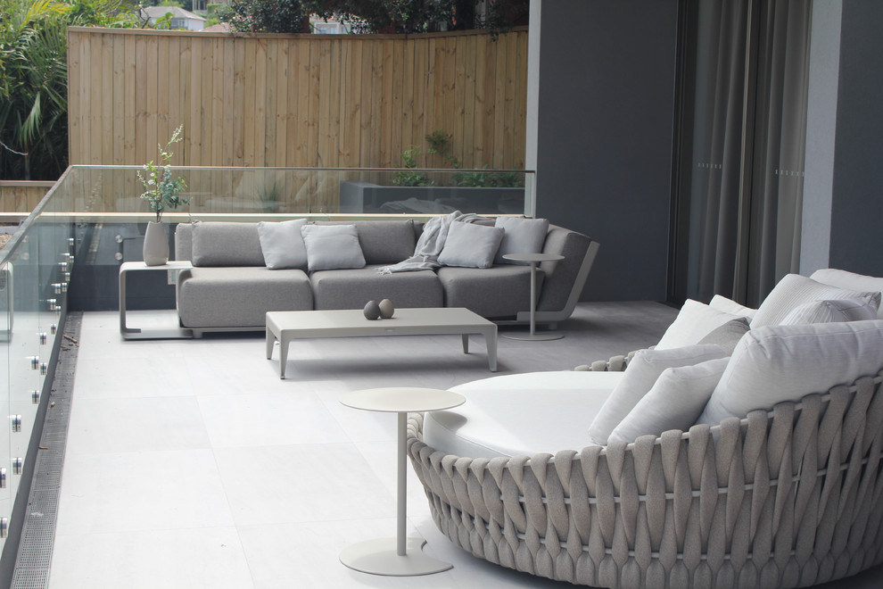 Medium sized modern back patio in Sydney with natural stone paving, an awning and a potted garden.