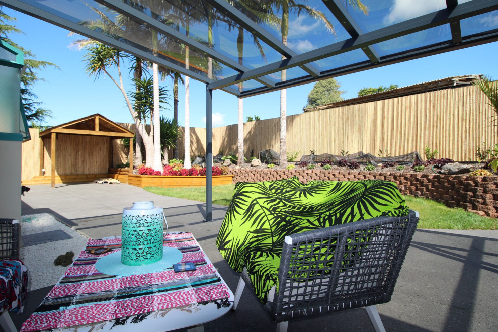 Esempio di un patio o portico tropicale di medie dimensioni e in cortile con lastre di cemento