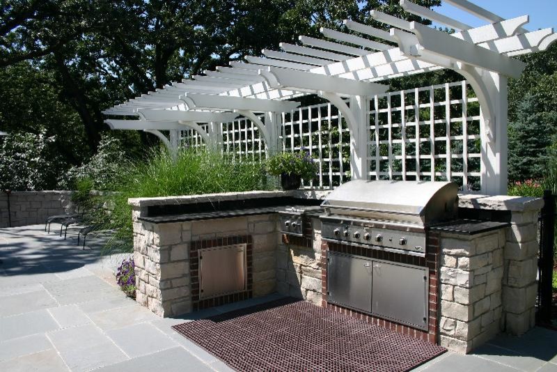 シカゴにある広いトラディショナルスタイルのおしゃれな裏庭のテラス (アウトドアキッチン、天然石敷き、パーゴラ) の写真