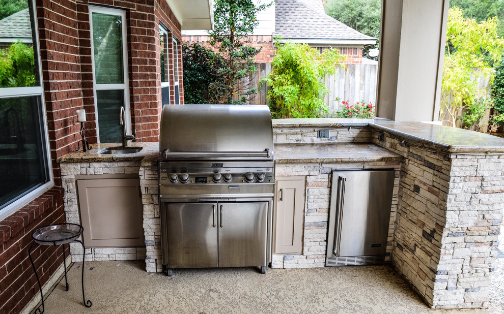 Example of a mid-sized classic backyard brick patio kitchen design in Houston with a roof extension