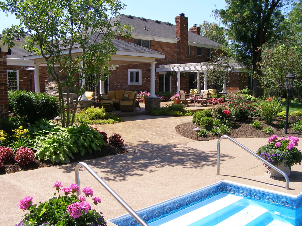 Foto di un grande patio o portico classico dietro casa con un focolare, pavimentazioni in cemento e una pergola