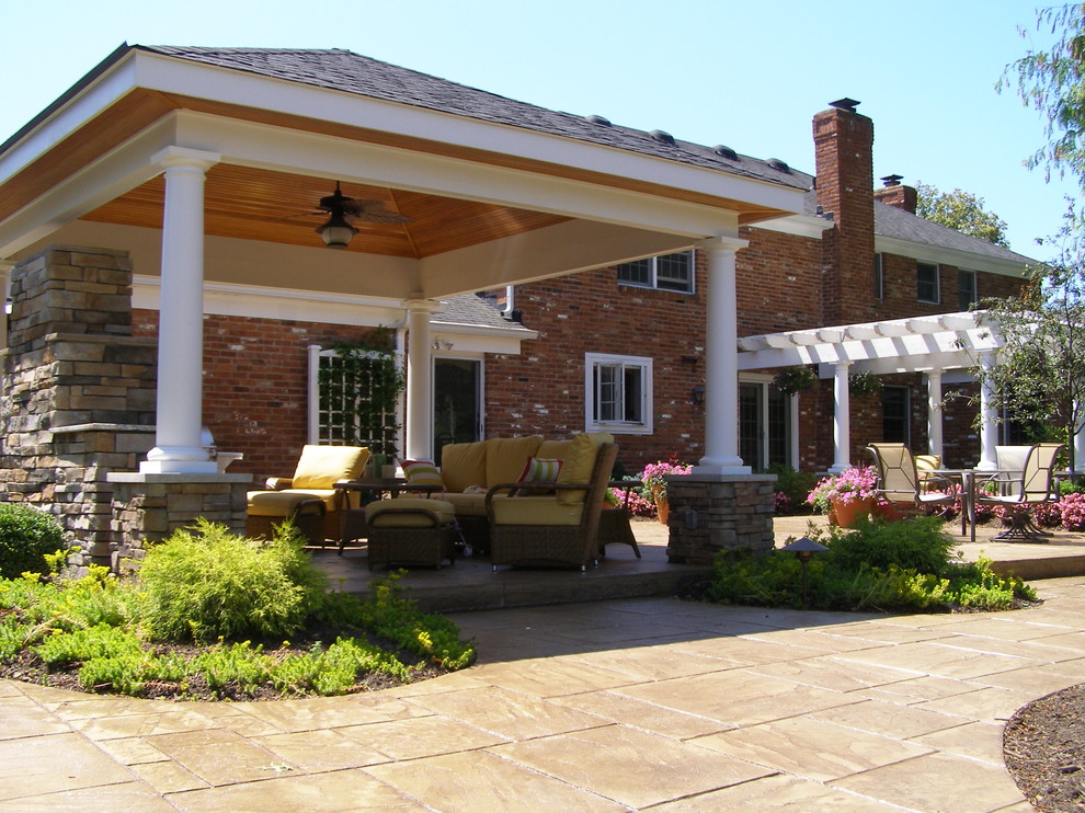 Immagine di un grande patio o portico classico dietro casa con un focolare, pavimentazioni in cemento e una pergola