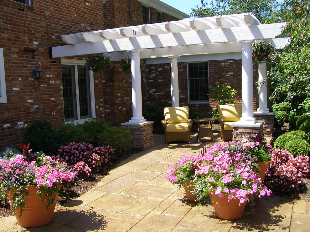 Inspiration pour une grande terrasse arrière traditionnelle avec un foyer extérieur, des pavés en béton et une pergola.