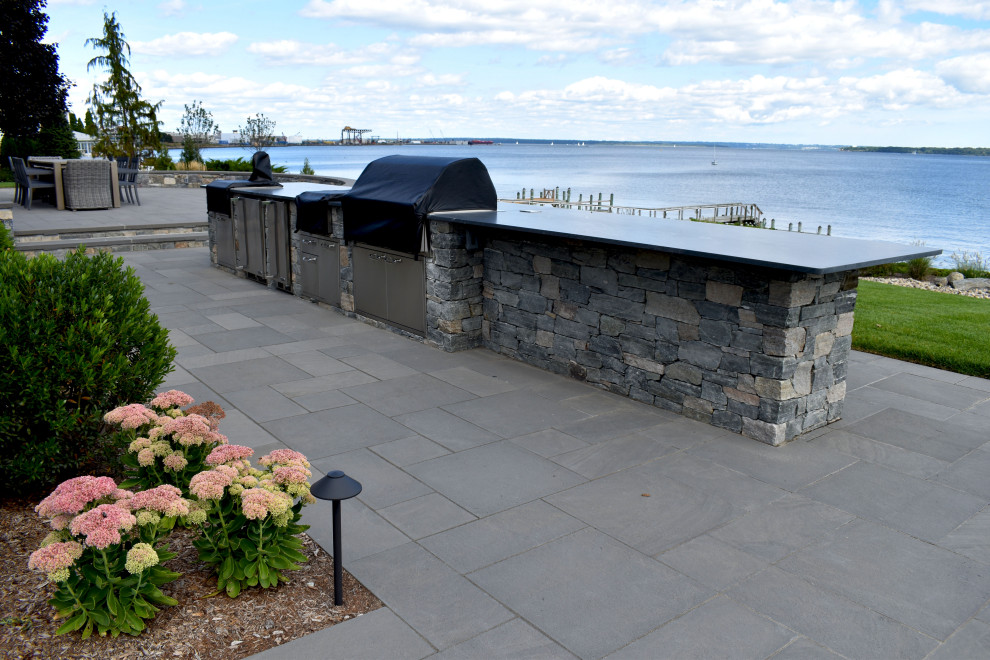 Exemple d'une grande terrasse arrière chic avec une cuisine d'été, des pavés en pierre naturelle et aucune couverture.