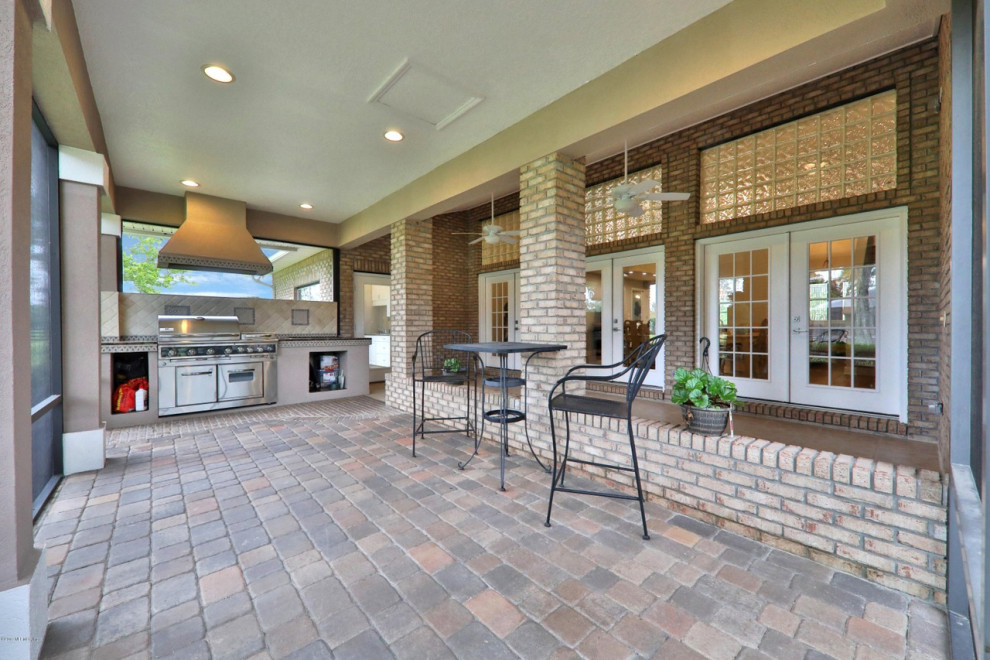 Patio kitchen - large french country backyard tile patio kitchen idea in Jacksonville with a roof extension