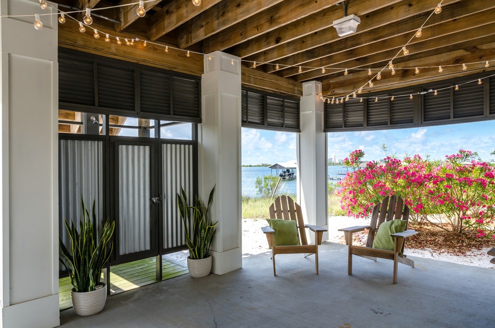 На фото: двор среднего размера на заднем дворе в морском стиле с покрытием из бетонных плит, навесом и летним душем