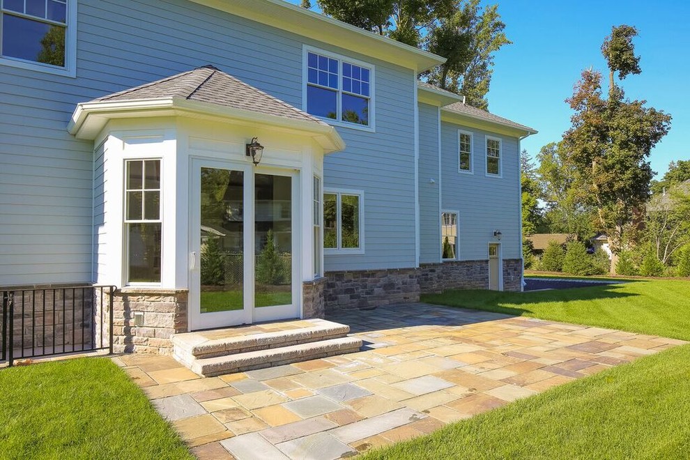 Example of a mid-sized transitional backyard stone patio design in New York with no cover