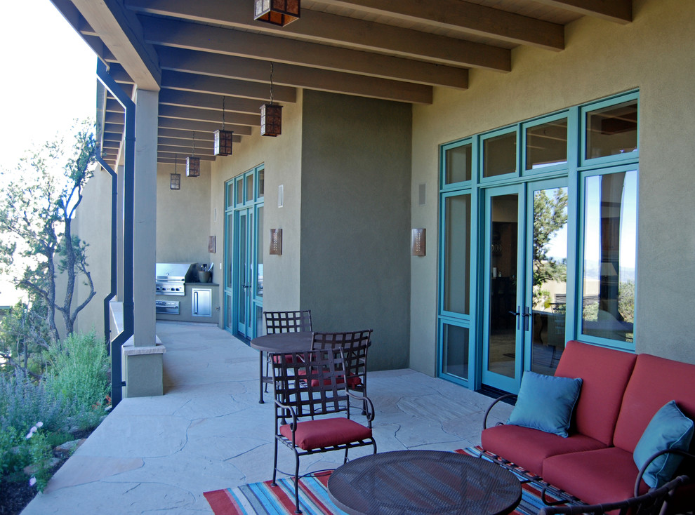 Cette photo montre une terrasse arrière tendance de taille moyenne avec une cuisine d'été, des pavés en pierre naturelle et une extension de toiture.