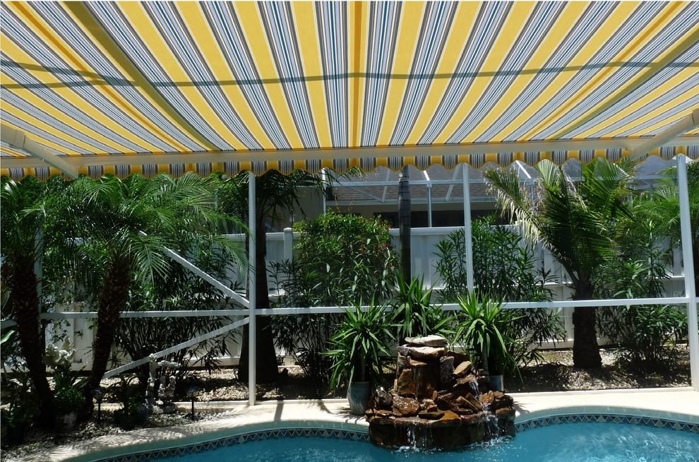 Example of an island style backyard tile patio fountain design in Orlando with an awning