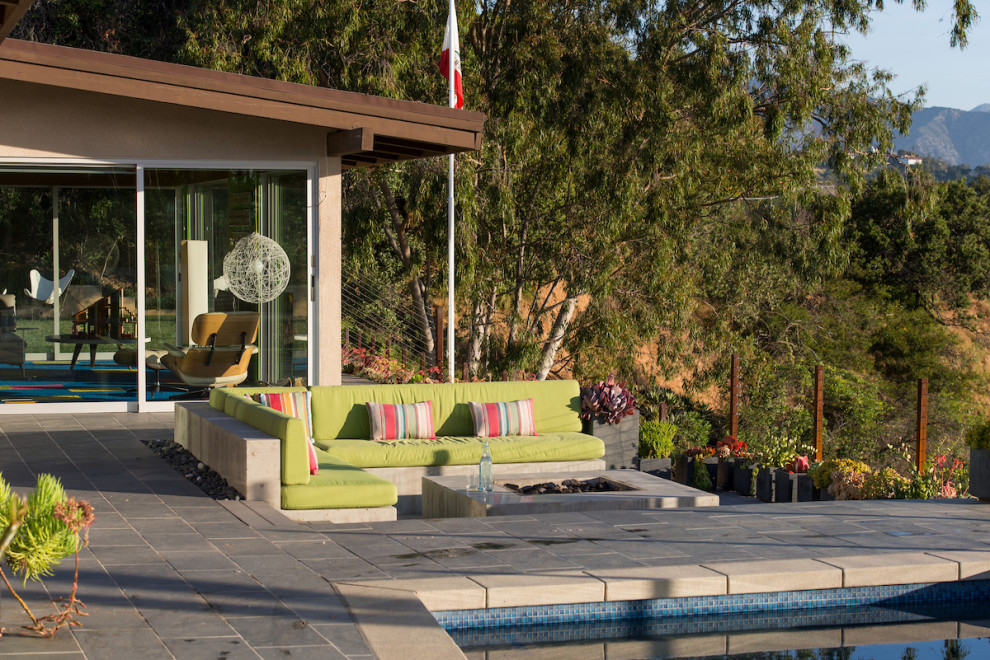 Unbedeckter Moderner Patio hinter dem Haus mit Feuerstelle und Natursteinplatten in Los Angeles
