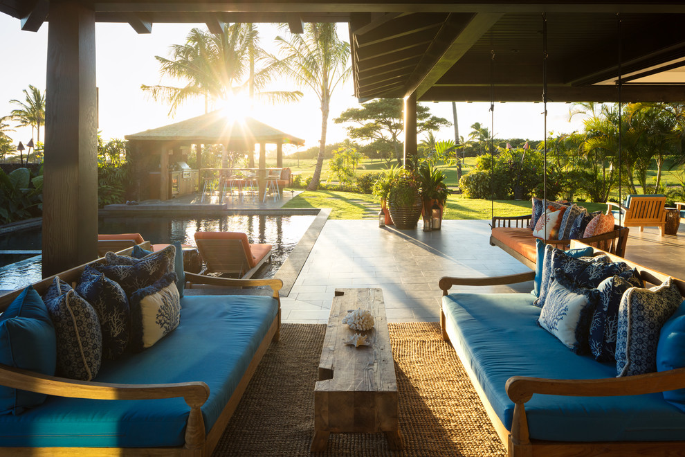 Réalisation d'une grande terrasse arrière ethnique avec une cuisine d'été, du carrelage et une extension de toiture.