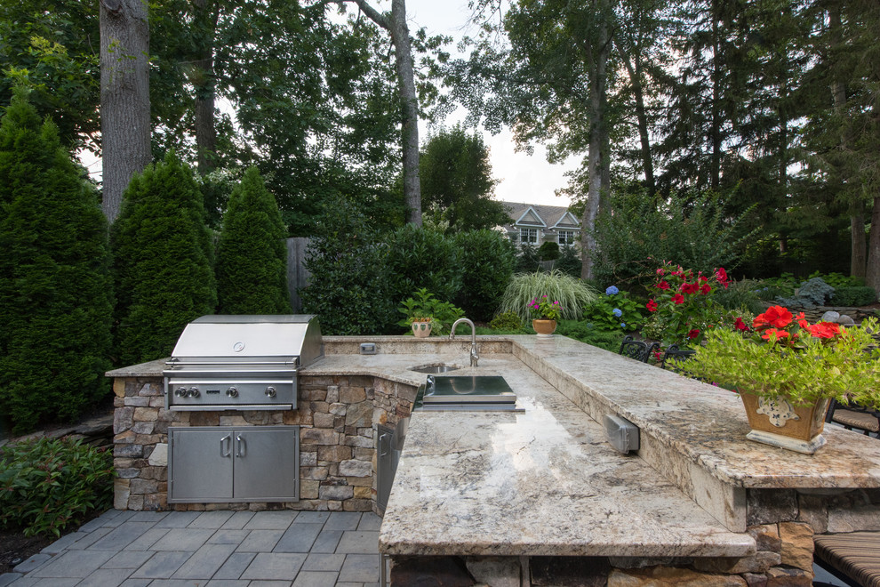 Inspiration for a large timeless backyard stone patio kitchen remodel in New York with no cover