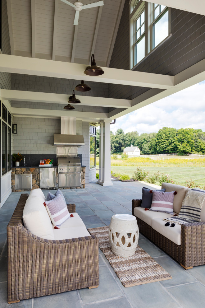 Cette photo montre une terrasse arrière nature de taille moyenne avec une cuisine d'été, des pavés en pierre naturelle et une extension de toiture.
