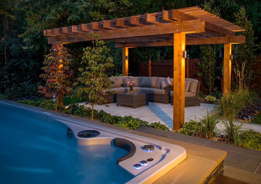 Diseño de patio contemporáneo de tamaño medio en patio trasero con fuente, adoquines de piedra natural y pérgola