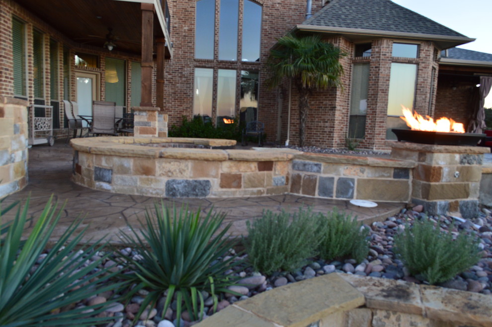 Example of a huge tuscan backyard stone patio design in Dallas with a fire pit and a roof extension