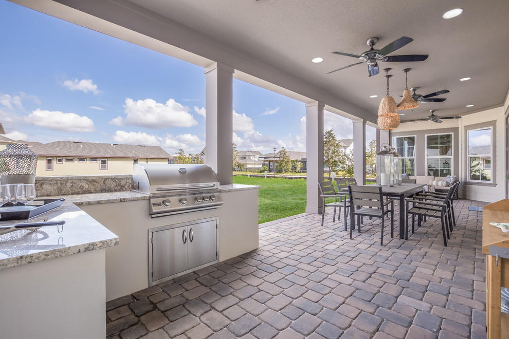 Example of a trendy side yard stone patio kitchen design in Orlando with a roof extension