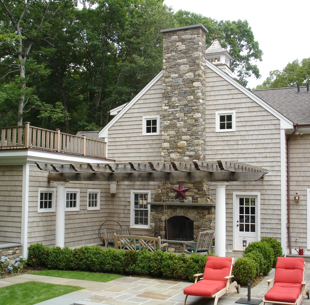 Example of a large classic backyard stone patio design in Other with a fire pit and a pergola