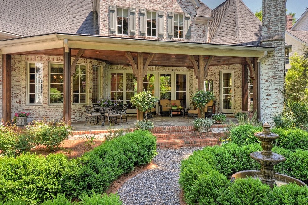 Immagine di un patio o portico chic di medie dimensioni e dietro casa con un focolare, pavimentazioni in pietra naturale e un tetto a sbalzo