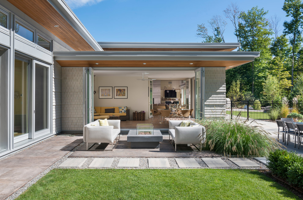 На фото: большой двор на заднем дворе в современном стиле с местом для костра, покрытием из бетонных плит и навесом с