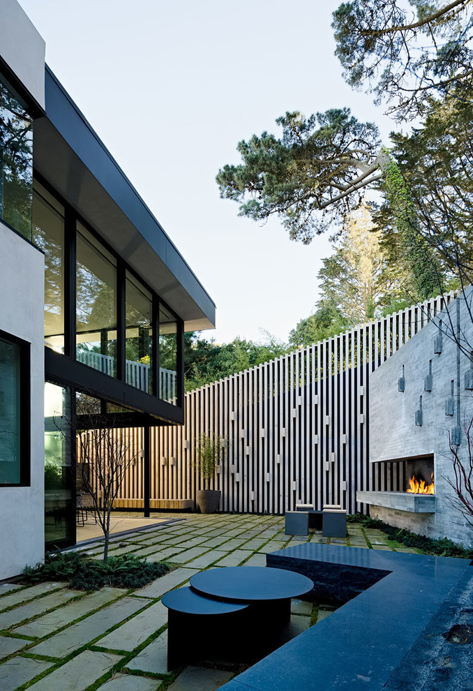 Inspiration pour une petite terrasse arrière minimaliste avec un foyer extérieur et des pavés en pierre naturelle.