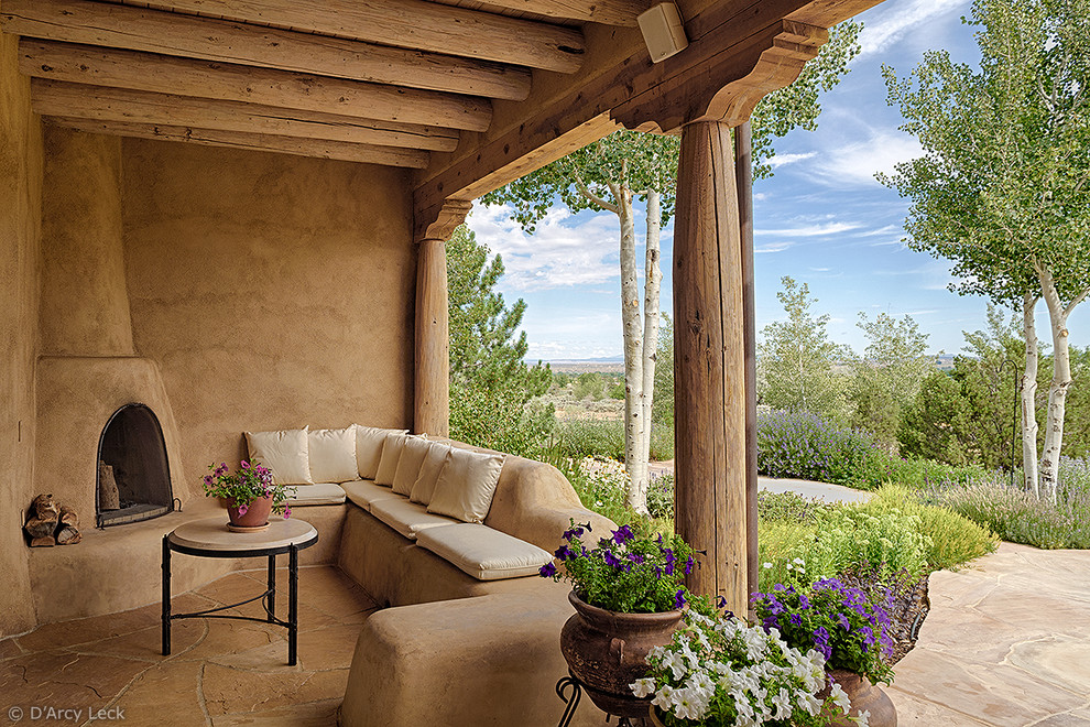 Idée de décoration pour une terrasse arrière sud-ouest américain de taille moyenne avec un foyer extérieur, des pavés en pierre naturelle et une extension de toiture.