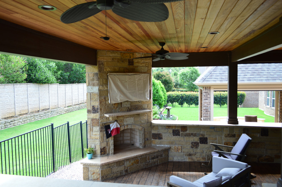 Mountain style backyard stamped concrete patio photo in Dallas with a fireplace and a roof extension