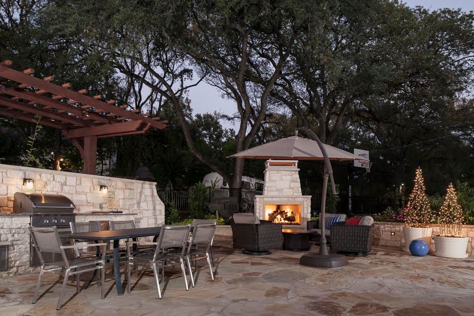 Design ideas for a large traditional back patio in Austin with an outdoor kitchen, natural stone paving and a pergola.