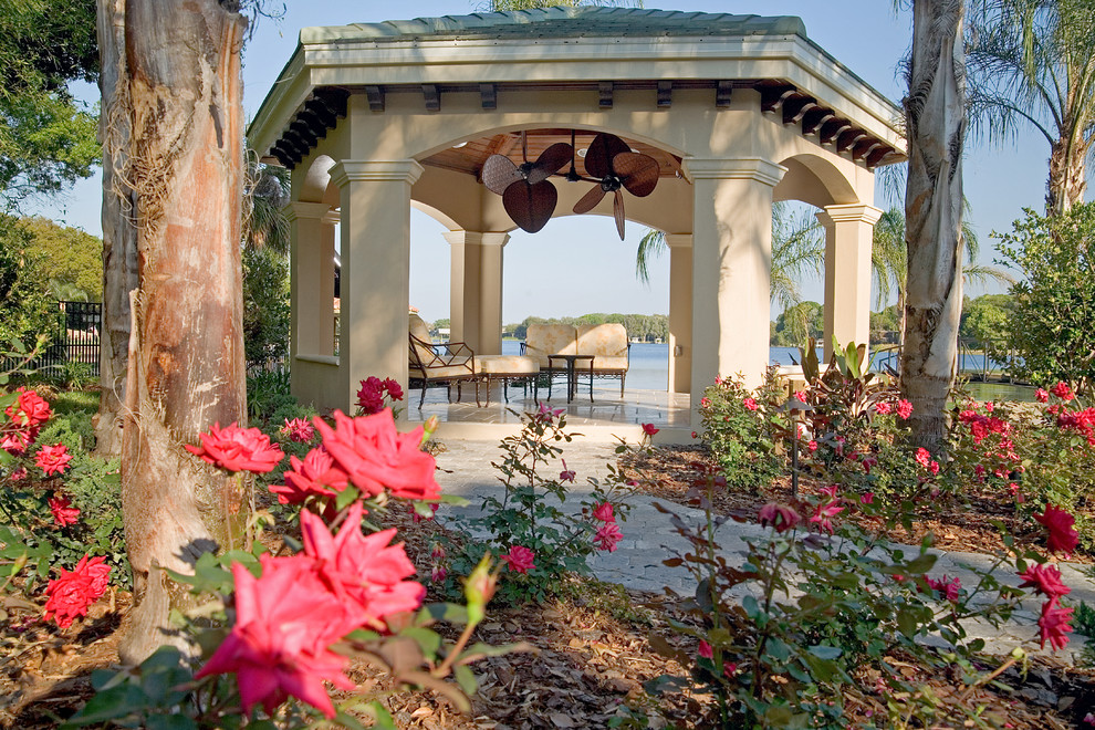 Foto di un grande patio o portico tropicale dietro casa con pavimentazioni in pietra naturale e una pergola