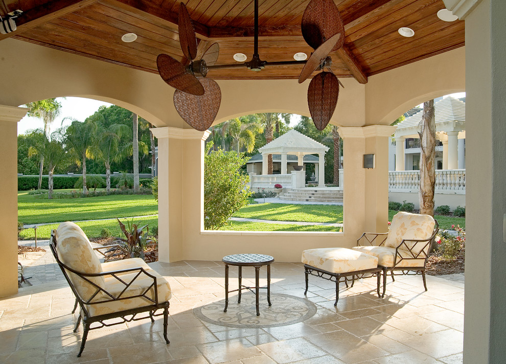 Idee per un grande patio o portico tropicale dietro casa con pavimentazioni in pietra naturale e una pergola
