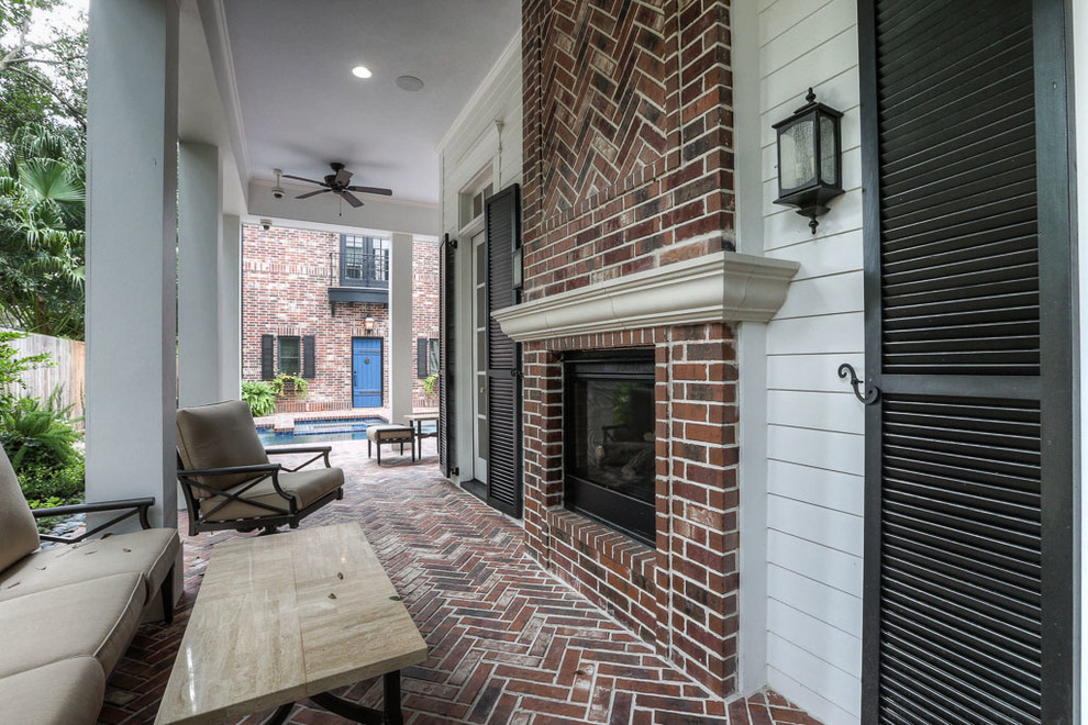 This is an example of a large classic back patio in Houston with brick paving and a roof extension.