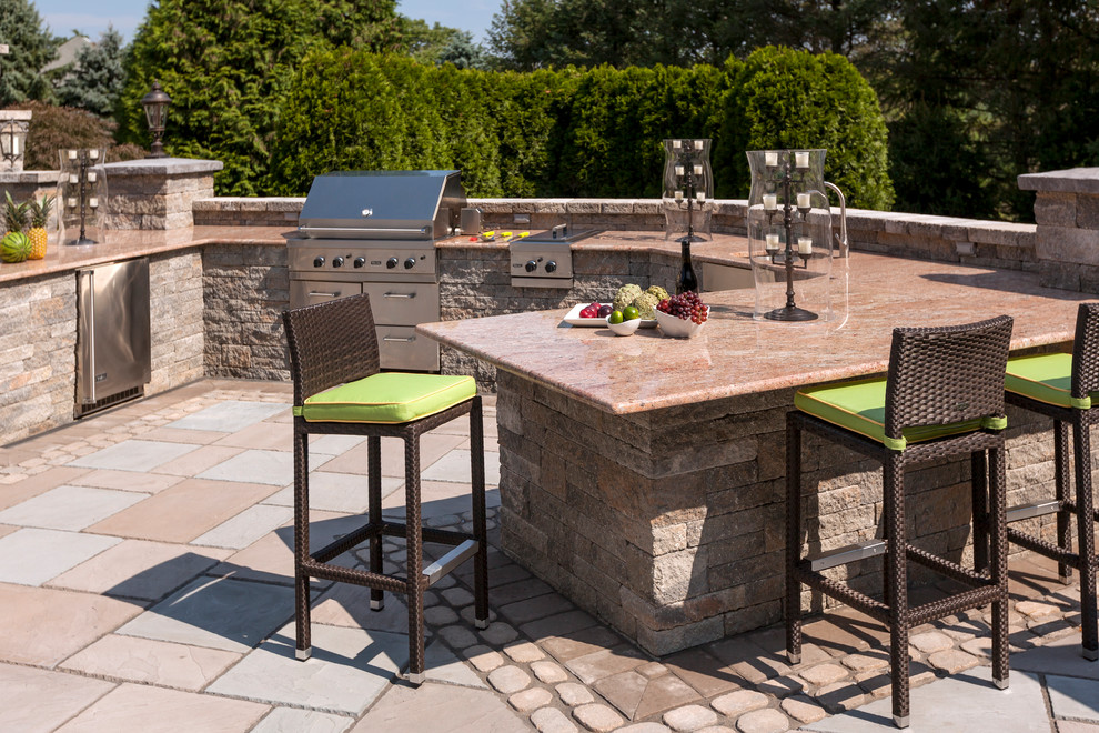 Example of a mid-sized classic backyard stone patio kitchen design in New York with no cover