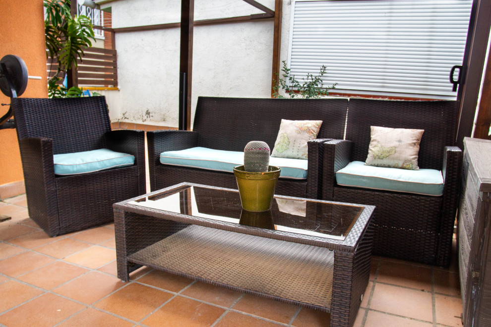 This is an example of a small rustic courtyard patio in Barcelona with tiled flooring and a pergola.