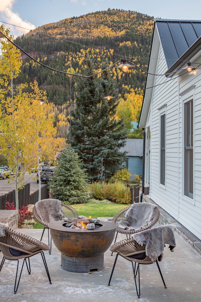 This is an example of a rustic side patio in Denver with a fire feature, concrete slabs and no cover.