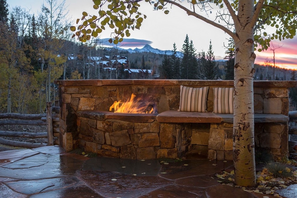 Large rustic back patio in Denver with a fire feature, natural stone paving and no cover.