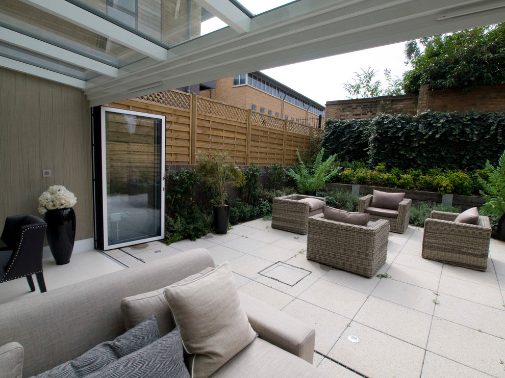 Photo of a small contemporary back patio in Cambridgeshire with a living wall, concrete paving and a roof extension.