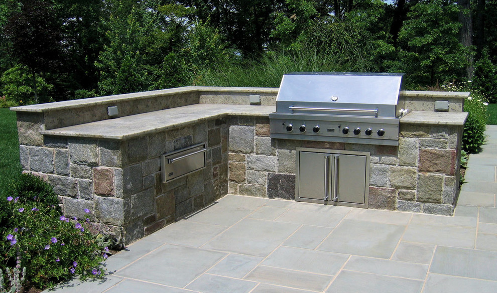Modelo de patio clásico sin cubierta en patio trasero con cocina exterior y adoquines de piedra natural