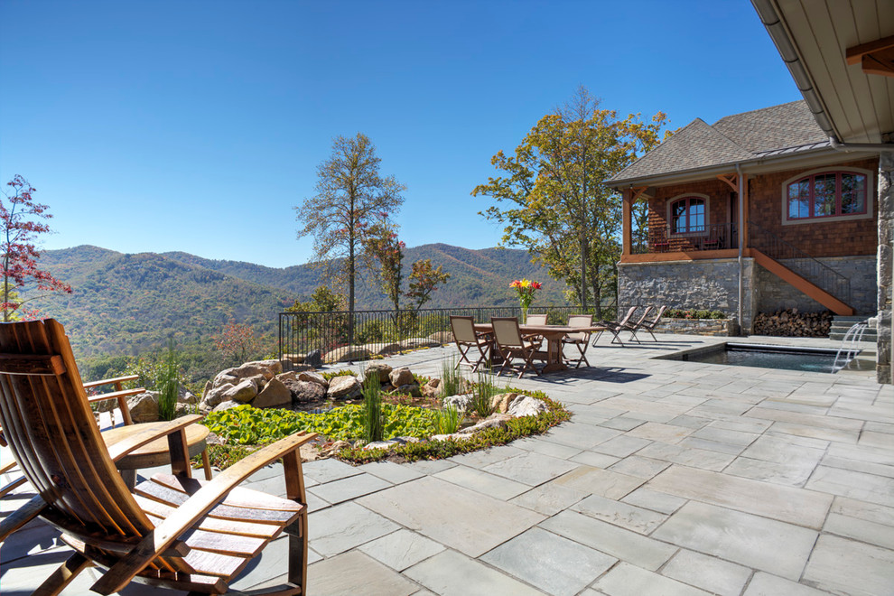 Photo of an expansive rustic back patio in Other with a water feature and natural stone paving.