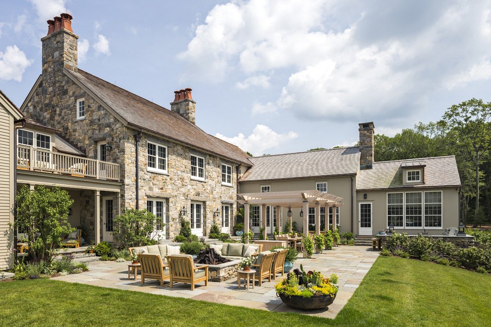 Foto di un ampio patio o portico tradizionale dietro casa con un focolare, pavimentazioni in pietra naturale e una pergola