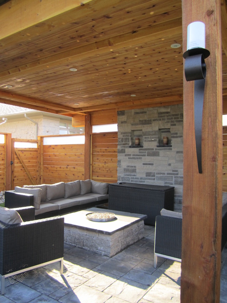 Design ideas for a large contemporary back patio in Toronto with natural stone paving and a pergola.