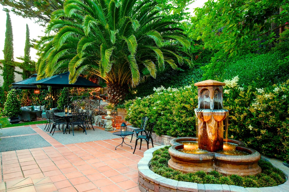 Ejemplo de patio mediterráneo extra grande en patio trasero con fuente, suelo de baldosas y cenador