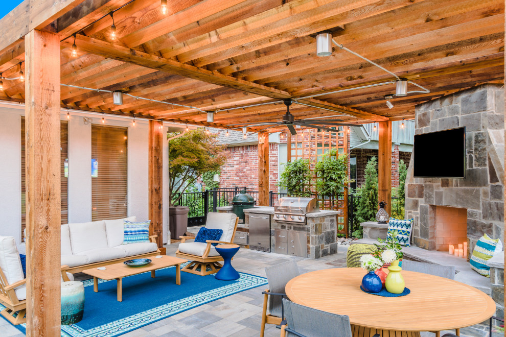 Idée de décoration pour une grande terrasse arrière tradition avec une cheminée, des pavés en béton et une pergola.