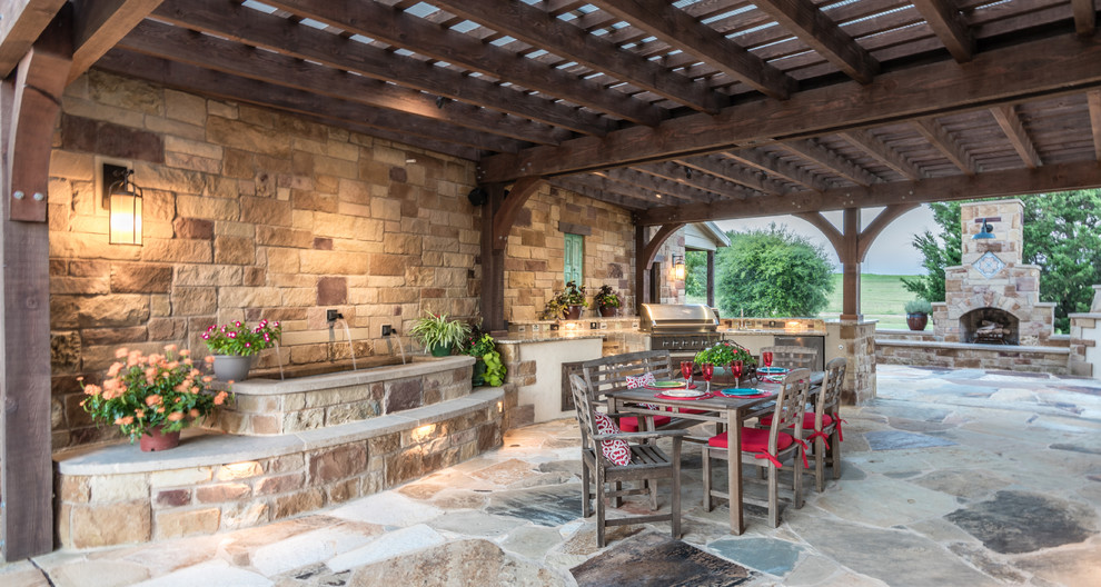 Inspiration for an expansive contemporary courtyard patio in Austin with an outdoor kitchen, a pergola and natural stone paving.