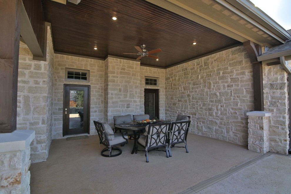 Cette photo montre une grande terrasse arrière chic avec un foyer extérieur, des pavés en béton et une extension de toiture.