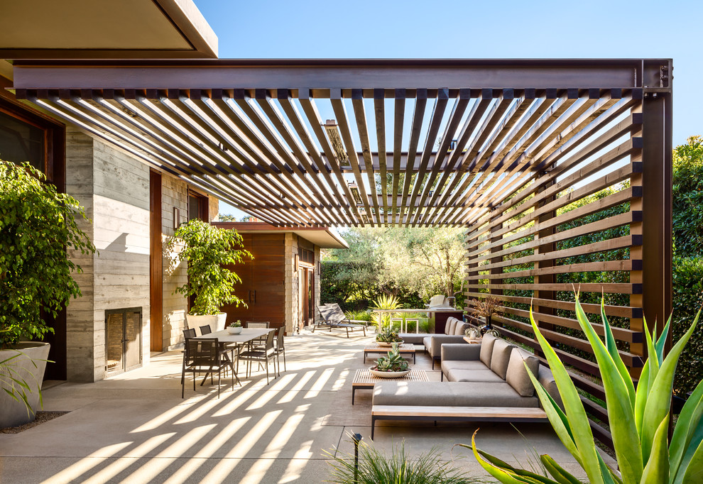 Example of a trendy concrete patio design in Santa Barbara with a pergola and a fireplace