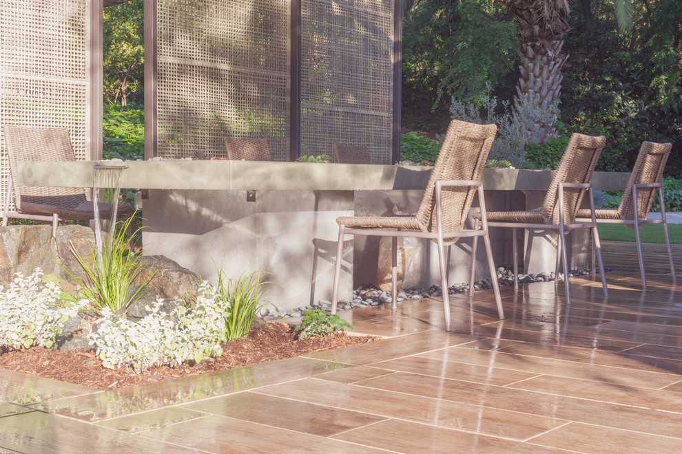 Design ideas for a modern back patio in Los Angeles with a water feature, natural stone paving and an awning.