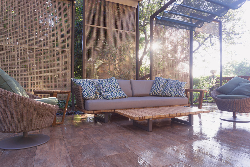 Cette image montre une terrasse arrière minimaliste avec un point d'eau, des pavés en pierre naturelle et un auvent.