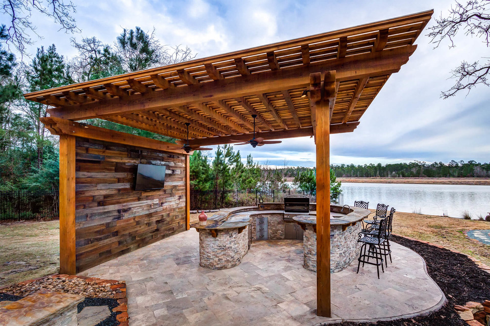 Modelo de patio rústico en patio trasero con cocina exterior, adoquines de piedra natural y pérgola