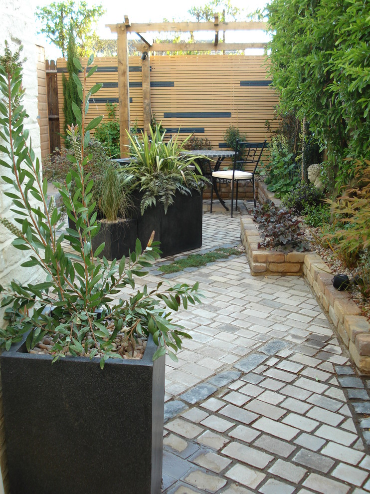 Imagen de patio ecléctico pequeño en patio trasero con adoquines de piedra natural