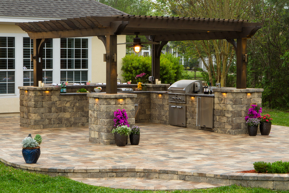 Inspiration for a large timeless backyard stone patio kitchen remodel in Jacksonville with a pergola